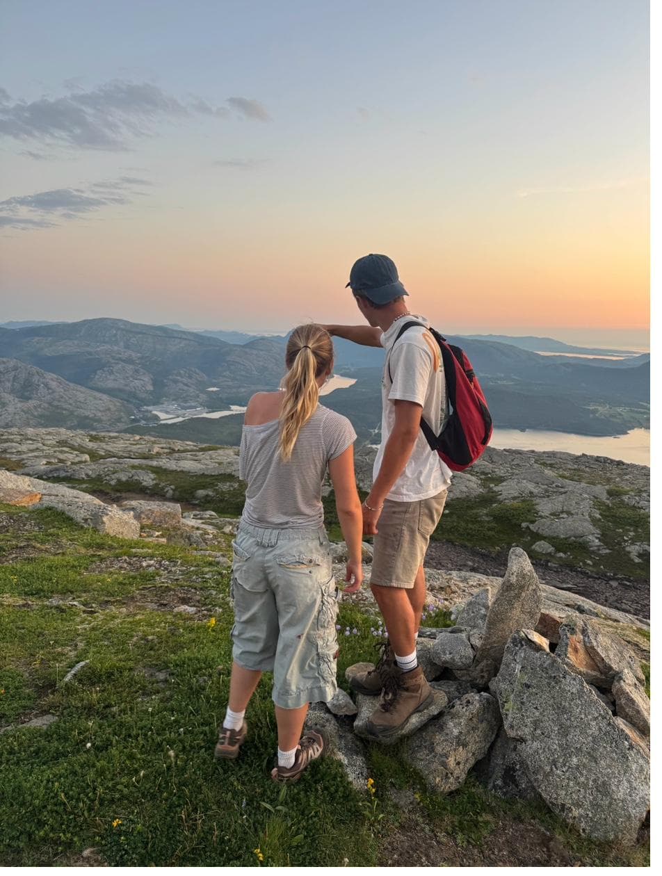 Two hikers at mountain summit at sunset