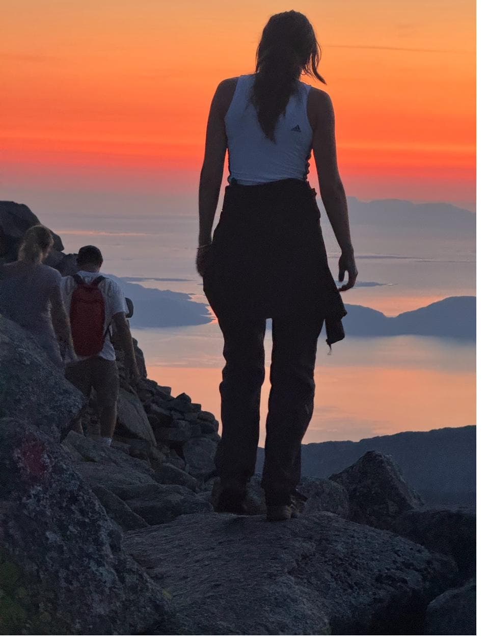 Silhouette of hiker against dramatic orange sunset