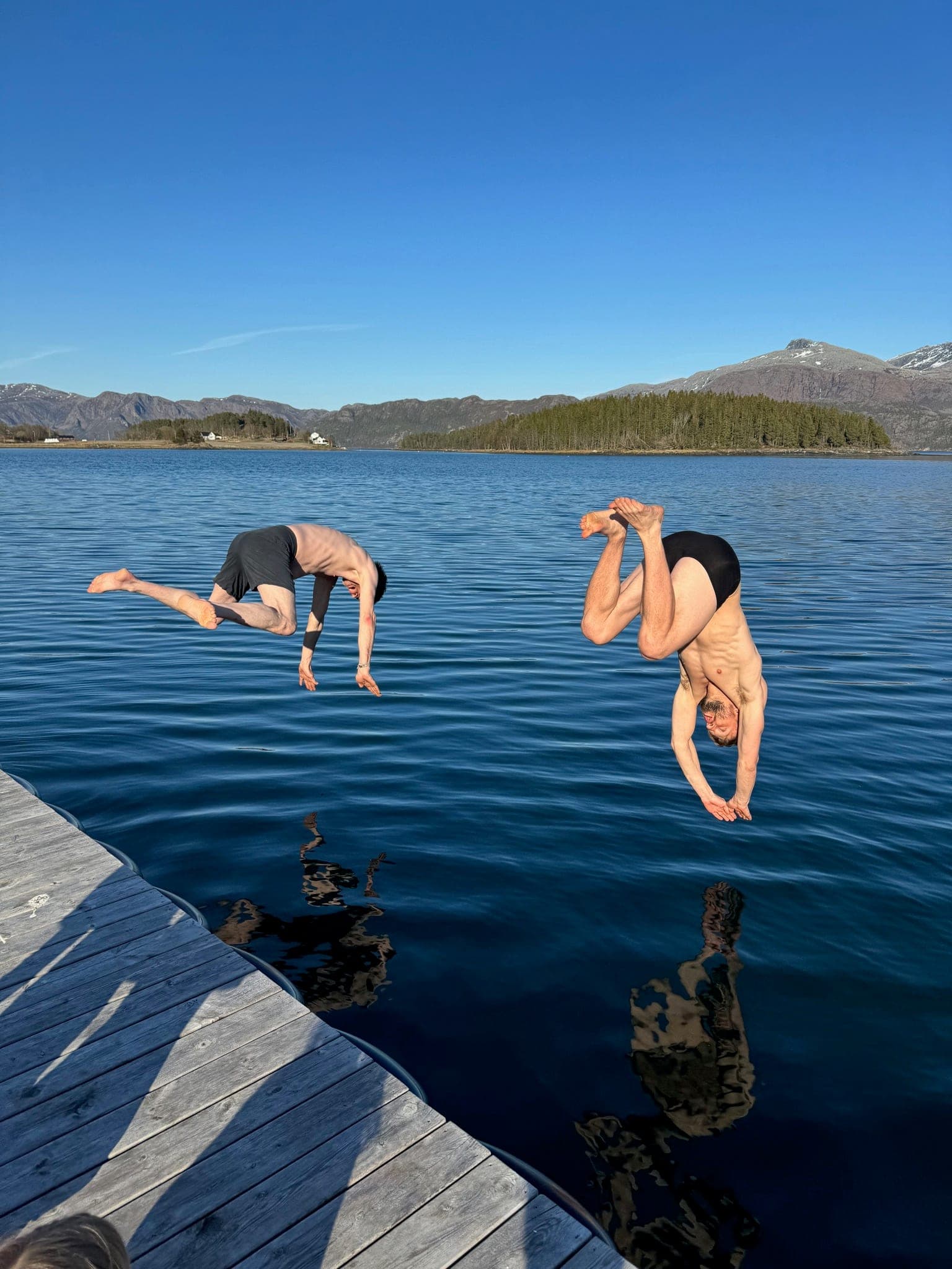 Person fishing from rocks in Norwegian sweater