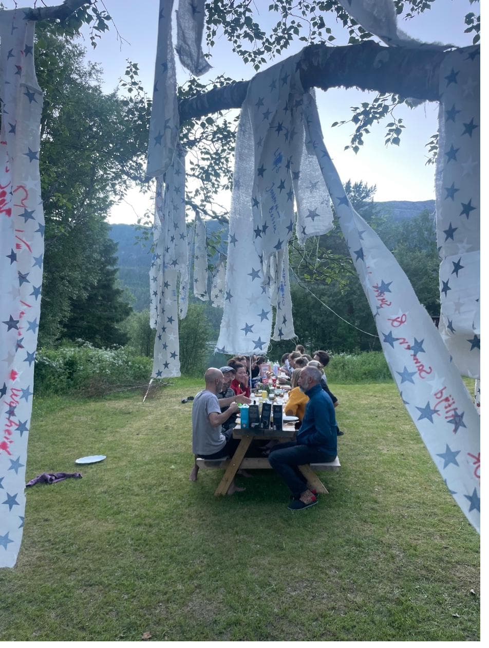 Community gathering at table under decorated fabric banners