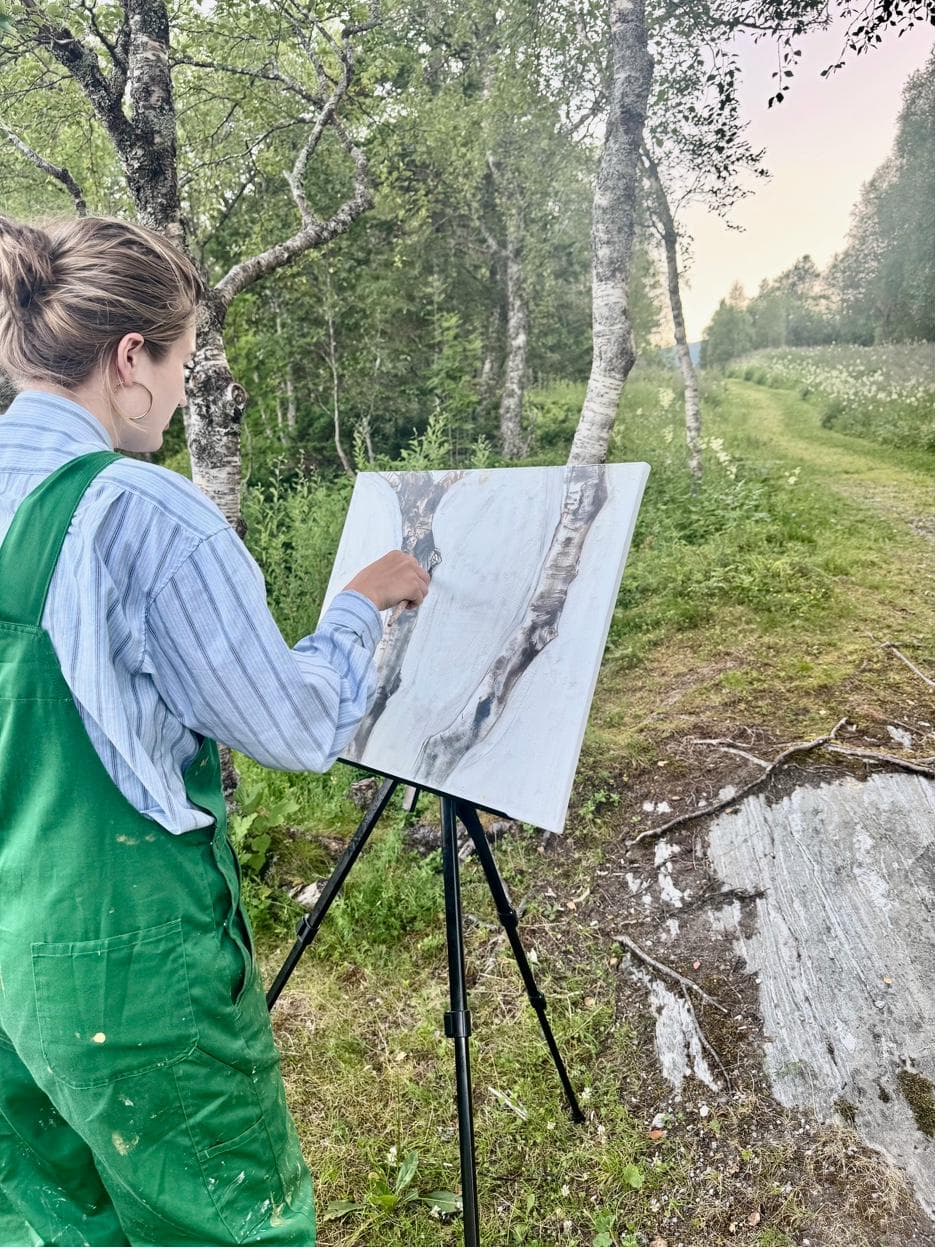 Artist painting at an easel among birch trees